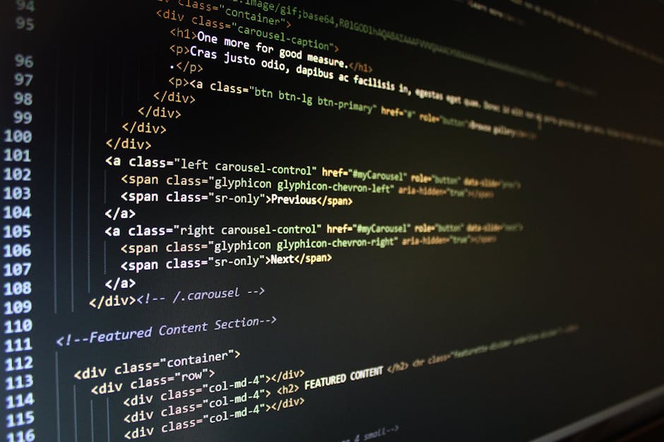 A close-up photograph of a computer screen displaying lines of programming code with syntax highlighting in various colors, including green, orange, and white. The code appears to be HTML, showing tag