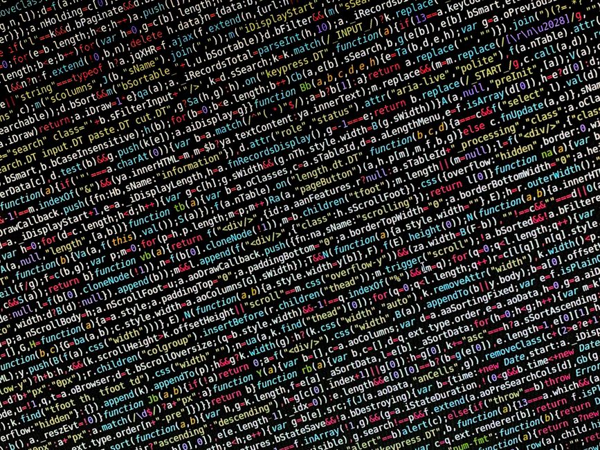 A close-up photograph of a computer screen displaying lines of programming code with syntax highlighting in various colors, including green, orange, and white. The code appears to be HTML, showing tag